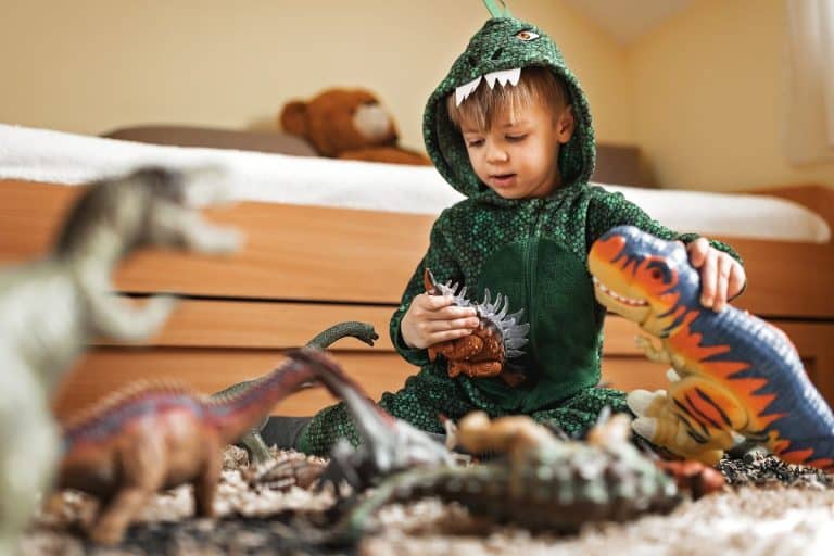 A toddler engaging in imagination play with dinosaur toys.